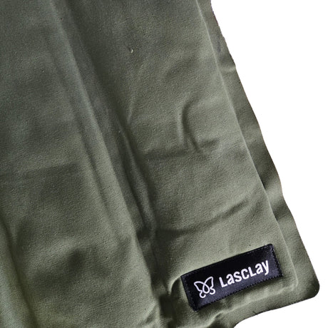Gros plan d'un coussin d'assise thermal pliable en toile de coton vert kaki garni de fibre d'asclépiade, étiquette Lasclay cousue, version imparfaite présentant de légères taches.