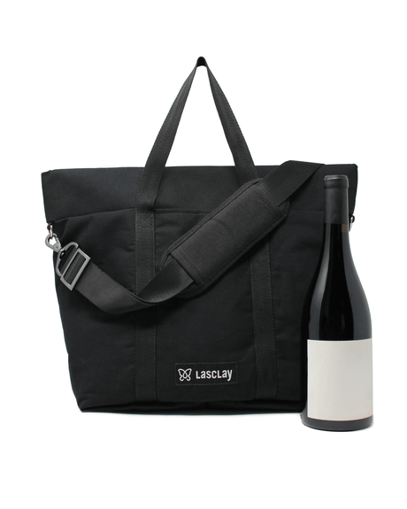 Besace isotherme en toile de coton noire doublée de nylon présentée avec une bouteille de vin, bandoulière ajustable et écusson Lasclay brodé, doublure isolée à la soie d'Amérique qui garde les bouteilles au frais.