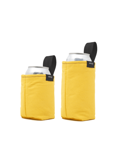 Deux manchons à canette isothermes Lasclay en coton jaune moutarde à pellicule réfléchissante, enfilés sur des canettes, formats régulier et grand, languette d'attache, doublés d'isolant à la soie d'asclépiade.