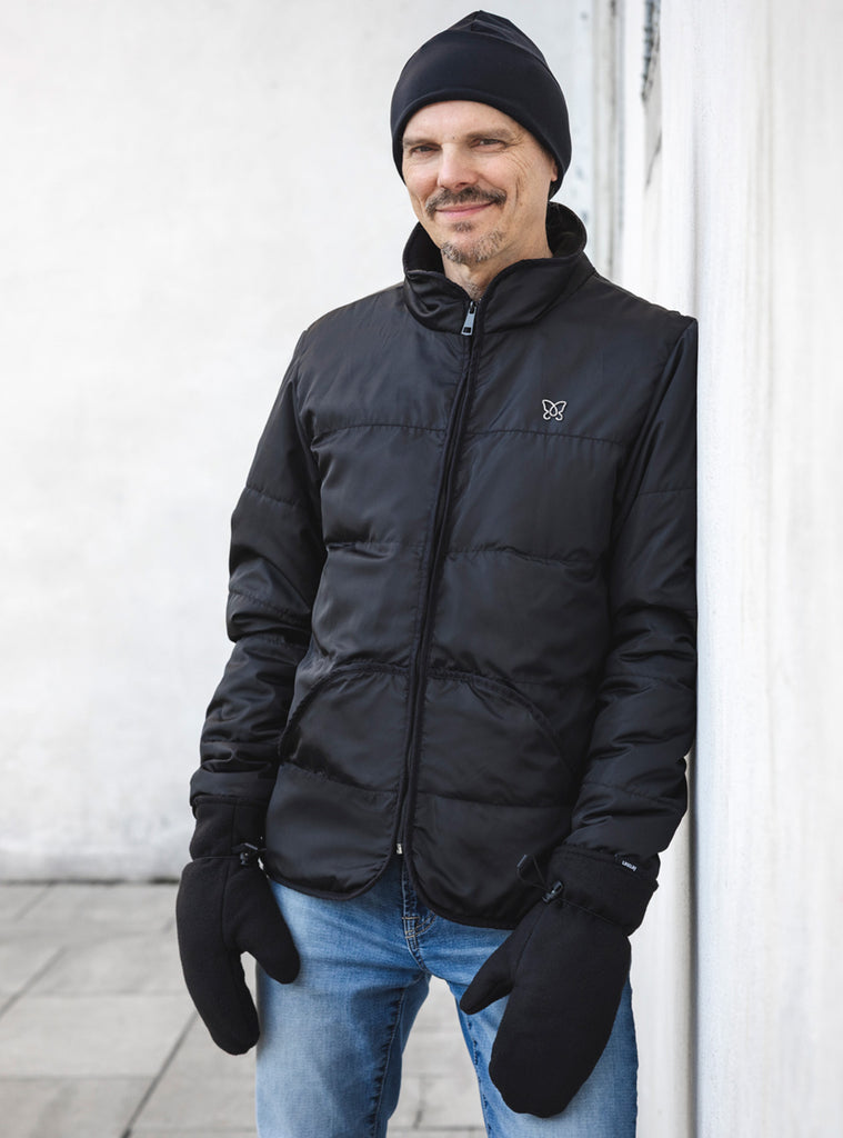 Homme portant un manteau noir et des mitaines isolées d'asclépiade de Lasclay fabriquées au Québec, dans un décor d'hiver