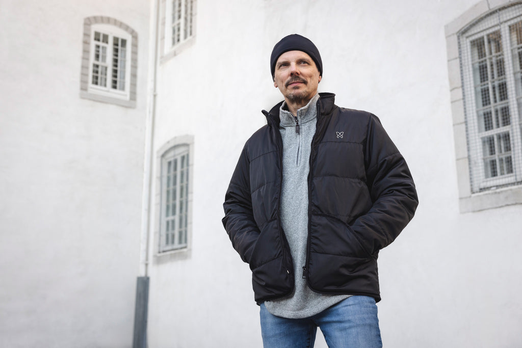 Homme avec tuque sport et mains dans les poches d'un manteau d'hiver d'asclépiade Lasclay devant le Petit Séminaire de Québec