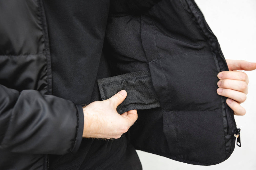 Homme montrant les coussins amovibles d'asclépiade, sortant d'une pochette intérieure de la veste sans manche Lasclay