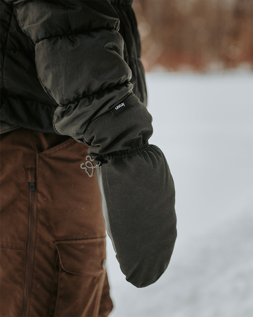 Mitaine noire Lasclay avec isolant d’asclépiade vue de côté, avec arrière plan hivernal flou. Fabriquées au Québec.