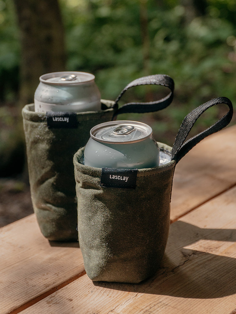 Paire de porte-canettes isothermes en coton, rembourrés de soie d'asclépiade et posés sur une table de bois en camping